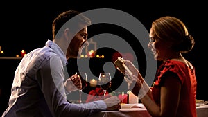 Woman holding precious present from beloved man, romantic evening in restaurant