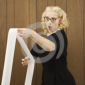 Woman holding a printout with a shocking expression on her face.