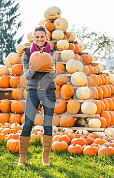 Woman holding pumpkin in front of pumpkin piramide photo