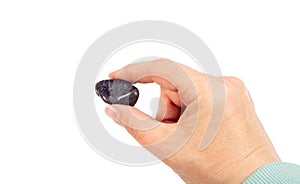 Woman holding purple color tumbled Iolite or Cordierite gemstone in hand, isolated on white background, lot of copy space.