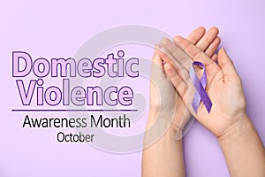 Woman holding purple ribbon on background, top view. Symbol of Domestic Violence Awareness