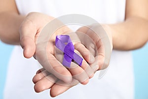 Woman holding purple ribbon on blue background. Domestic violence awareness