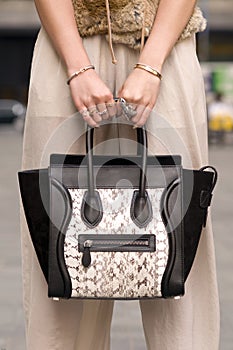 Woman holding purse, handbag with rings on fingers