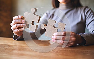 A woman holding and putting a piece of wooden jigsaw puzzle together