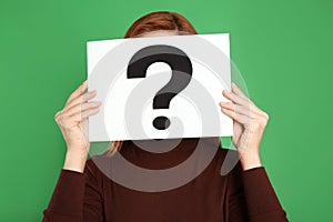 Woman holding question mark sign on background
