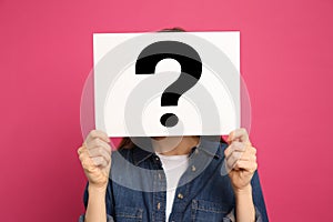 Woman holding question mark sign on background