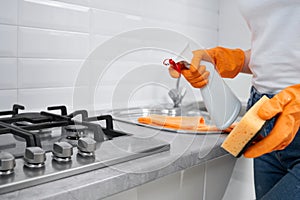 Woman holding rag and detergent for cleaning cooker.