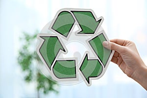 Woman holding recycling symbol on blurred background