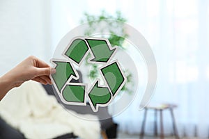 Woman holding recycling symbol on blurred background, closeup