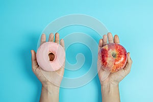 Woman holding red apple and pink donut, female choose between fruit is Healthy food and sweet is unhealthy junk foods. Dieting,
