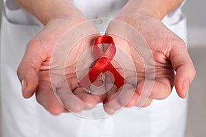 Woman holding red awareness ribbon, closeup. World AIDS disease day