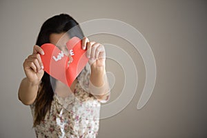 Woman holding red broken heart with love text.