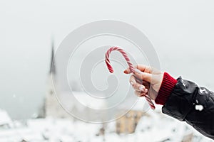 Woman holding red candycane with Hallstatt old town on background, Austria