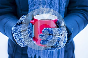 Woman holding red cup with hot drink in winter