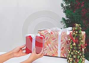 Woman holding red gift box on white table. Christmas or birthday present and thanksgiving, more give the more receive concept.