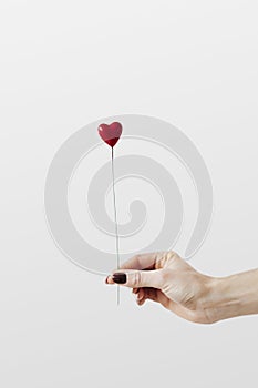 Woman holding a red heart on a stick