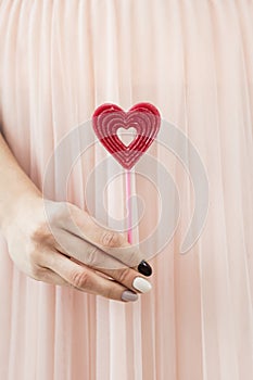 Woman holding a red heart on a stick