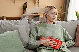 Woman Holding Red Hot Water Bottle to Stomach