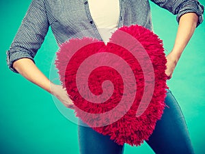 Woman holding red pillow in heart shape