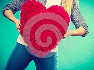 Woman holding red pillow in heart shape