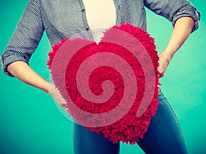 Woman holding red pillow in heart shape