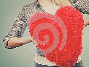 Woman holding red pillow in heart shape