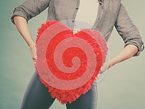 Woman holding red pillow in heart shape