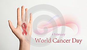 Woman holding red ribbon on background, top view. World Cancer Day