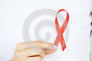 A woman holding a red ribbon emerges from a critical situation after overcoming AIDS