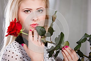 Woman holding red rose near face looking melancholic