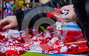 Woman holding red and white traditional martisor and martenica in her hand outdoors.