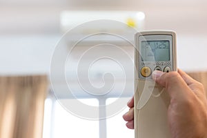 Woman holding a remote control with air conditioner,controlling the temperature,adjust air conditioner to 25 degrees celsius,