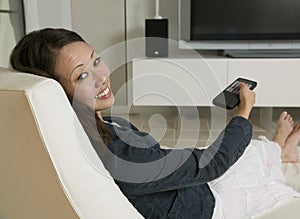 Woman Holding Remote Control While Sitting On Chair
