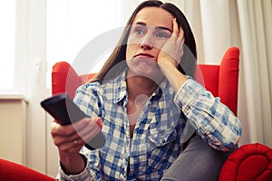 Woman holding remote control and watching tv