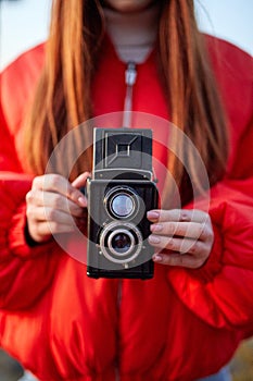 Woman holding retro camera in hands, focus on camera