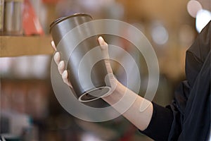 A woman holding reuse black coffee bottle in coffee cafe