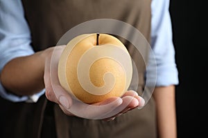 Woman holding ripe apple pear on black background, closeup