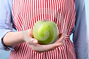 Woman holding ripe green apple, closeup view