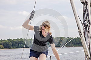 Woman holding ropes walking across deck of sailboat