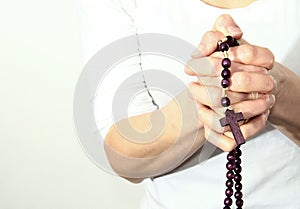 Woman holding a rosary beads cross in her hands