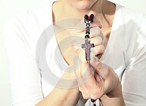 Woman holding a rosary beads cross in her hands