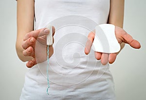 Woman holding sanitary napkin and tampon.