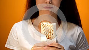 Woman holding shawarma, cheap delicious but unhealthy food, addiction