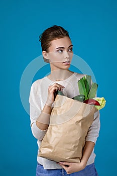Woman holding a shopping bag full of groceries