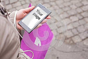 Woman holding shopping bag and mobile phone.