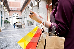 Woman holding shopping bag and using smartphone for shopping online, shopping concept