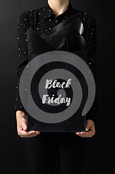 Woman holding shopping bag with words Black Friday on dark background, closeup