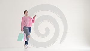 Woman holding shopping bags and pointing