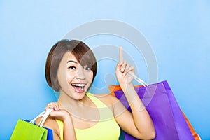 woman holding shopping bags and pointing up