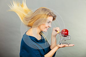 Woman holding shopping cart with apple inside